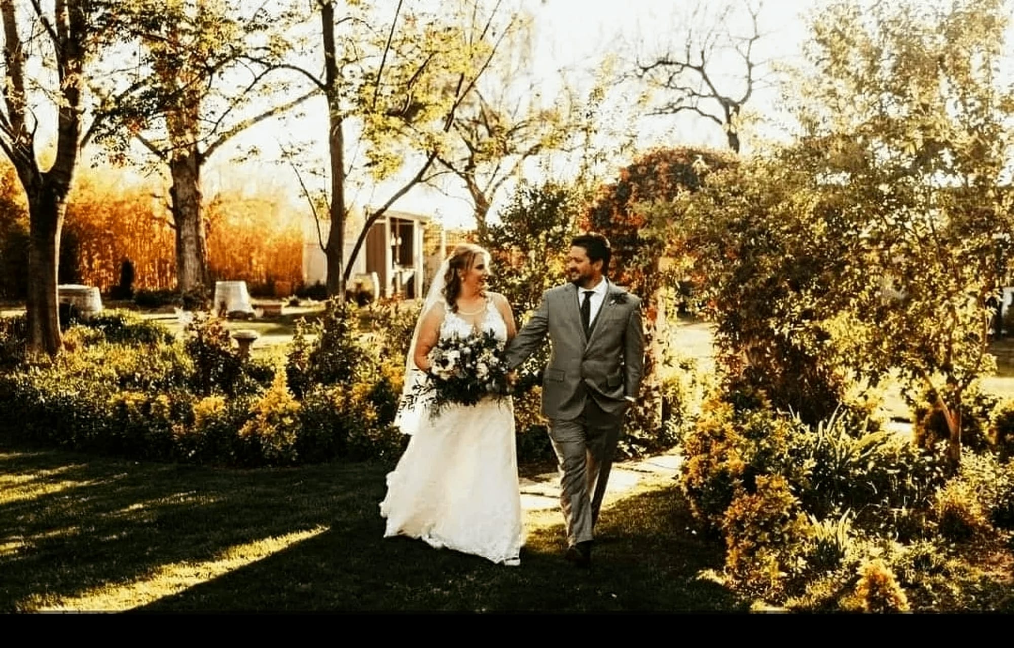 A couple walking a garden path between autumn trees at Kallista Park.